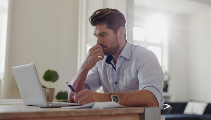 Man sitter vid ett skrivbord och arbetar vid en dator 