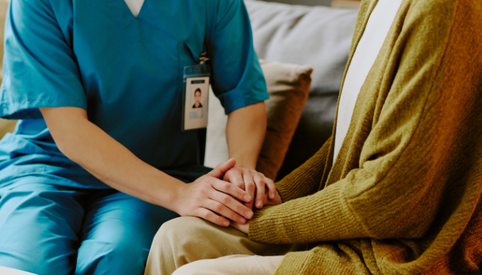 A care taker gently holding the hands of a patient