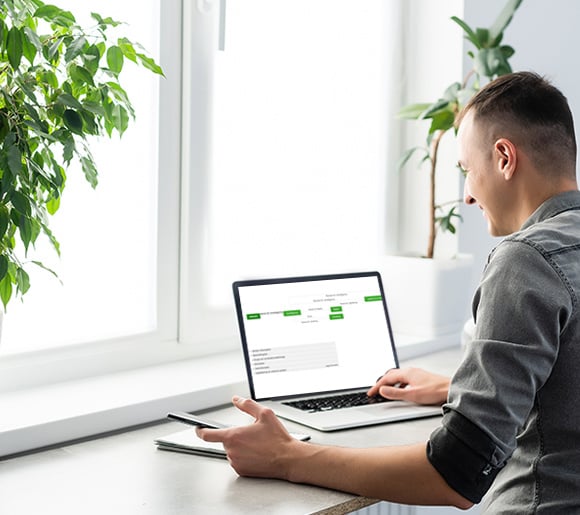 picture of a man sitting by a window writing on his screen
