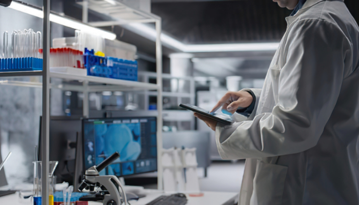 Scientist in a lab coat using a tablet in a modern laboratory.