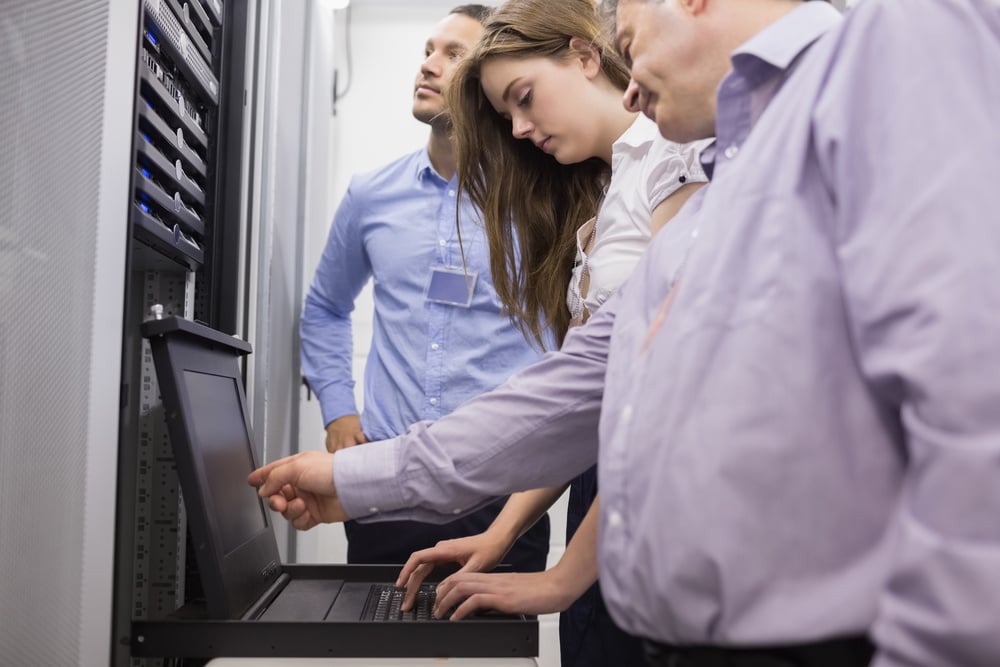 Technicians checking servers with laptop in data center