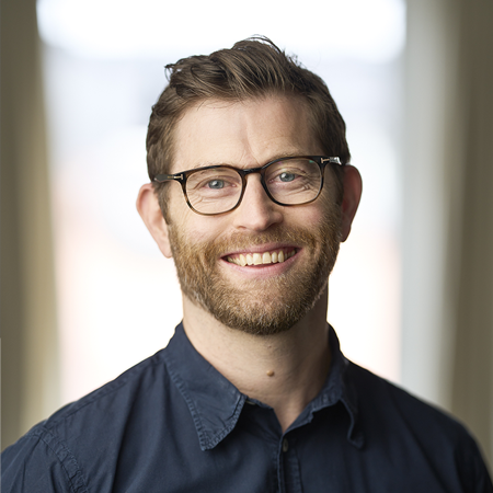 bild på leende man i blå skjorta och glasögon