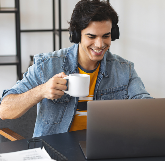 man med blå skjorta och en kaffekopp framför en dator